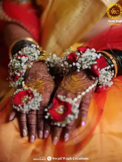 The beauty is in the details. This close-up shows the intricate work that goes into each hathphool, combining delicate baby's breath with bold red flowers to create a stunning contrast against the bride's henna.