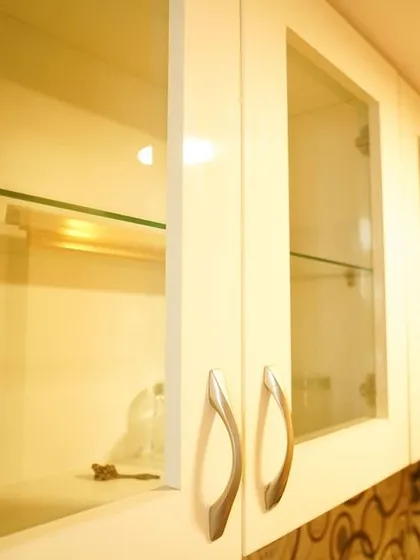 A close-up of the glass-fronted upper cabinets, showing the simple yet elegant storage for glassware. The patterned backsplash is visible in the background, adding depth to the design.
