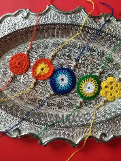 A vibrant assortment of my simple and elegant crochet rakhis, laid out on a traditional silver platter. Perfect for showing the variety available.