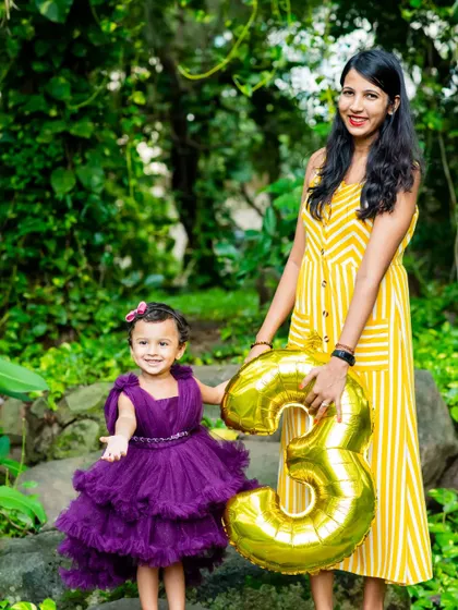 A proud mom and her three-year-old daughter posing with a birthday balloon. This outdoor pre-birthday shoot is a great way to get beautiful portraits before the big party.