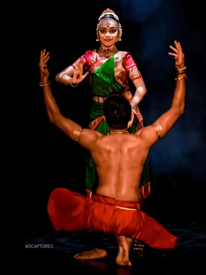 A back view of a pose from 'SUTÃ', showing the strength and grace required for the performance. The lighting highlights the musculature and form of the dancers.