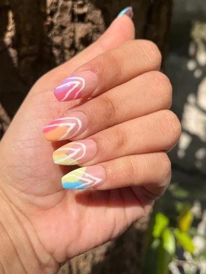 A client's hand showcasing her custom rainbow gradient nails. The press-ons are sized perfectly to her natural nail bed, making them look seamless and realistic.