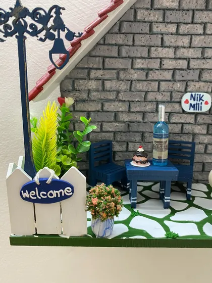 Look at the tiny details on this diorama, from the welcome sign on the fence to the miniature wine bottle and cake on the table. It’s these little touches that bring the scene to life.