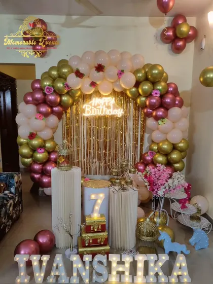 A 7th birthday party setup with a gold, rose gold, and cream balloon arch.