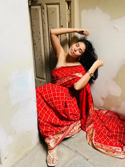 An artistic pose in a rich red Bandhani saree, conveying a dramatic and emotive mood for a high-fashion concept.