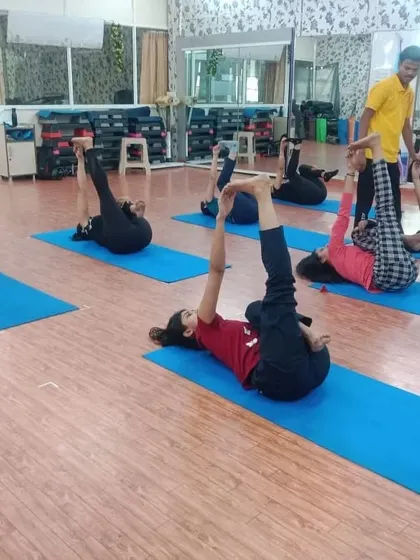 A class in progress, with students holding a leg-stretching asana. The mirrored walls in our studio help you self-correct your posture and observe your alignment, an important skill for any aspiring yoga teacher.
