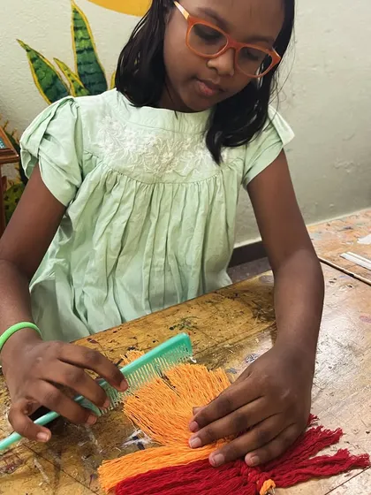 Combing out the fringe on a macrame piece is a satisfying final step. This student is adding the finishing touches to her colorful creation.