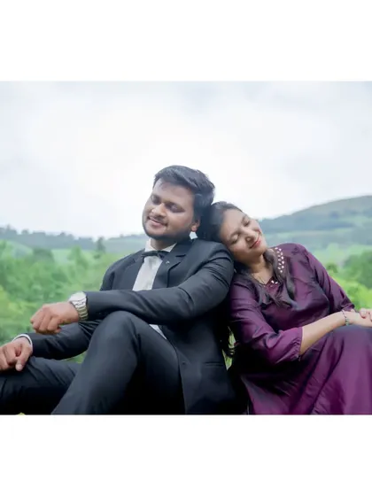The couple sits back-to-back, enjoying a peaceful moment together in nature. This pose is great for creating a sense of relaxed companionship.