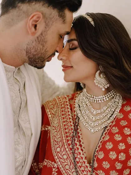 A duplicate of image 16, this intimate close-up of the couple highlights the bride's magnificent layered Tyaani Jewellery necklace and statement earrings, which were the centerpiece of her wedding look.