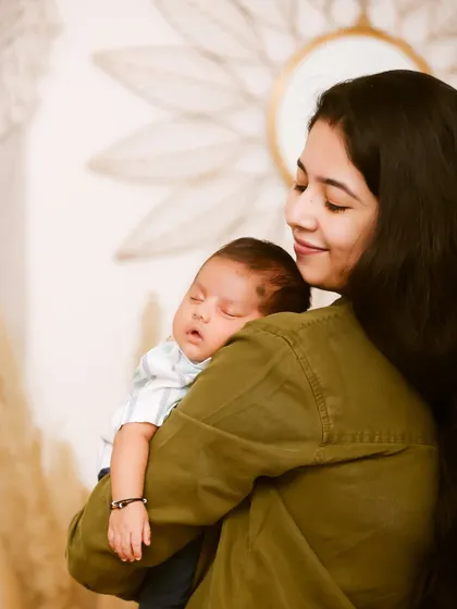 A mother's love captured in a quiet moment. She holds her sleeping newborn close, a simple and powerful portrait of the bond between mother and child.