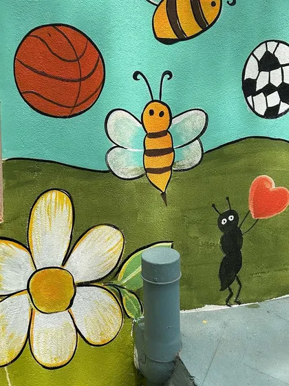 This part of the mural includes sports balls, friendly bees, and an ant holding a heart, adding playful and sweet elements.