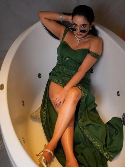 An overhead shot that provides a unique perspective, showcasing the full length of the green gown and the model's powerful pose within the tub.