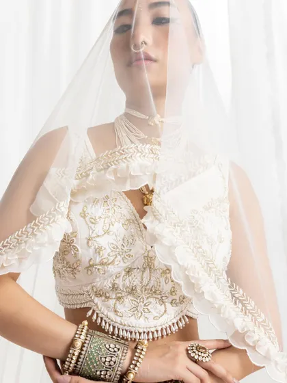 A more subtle view of the layered jewellery, with a sheer veil adding a touch of mystique. The focus is on the large Polki bangles and rings.