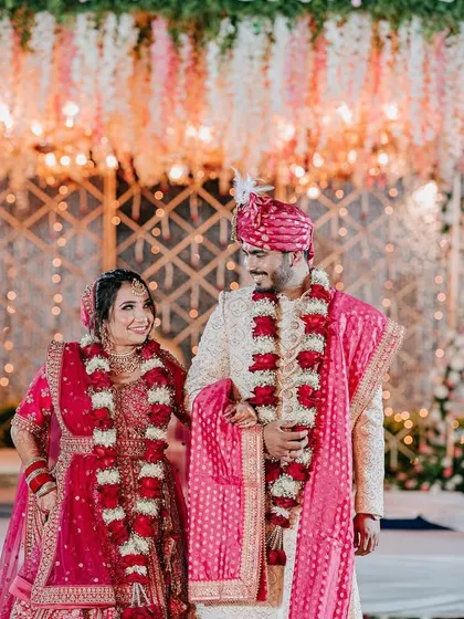 The couple stands together at their surreal mandap, surrounded by suspended florals and golden accents.