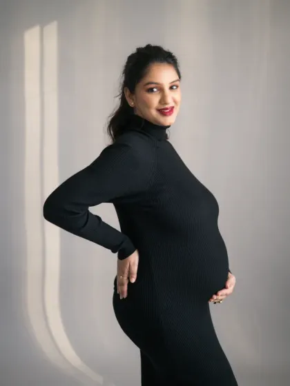 A stunning profile shot of the mother-to-be, showcasing her beautiful baby bump. The simple, clean background and soft lighting create a timeless and elegant maternity portrait.