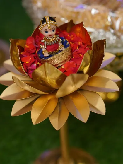 A small, adorable doll seated in a brass lotus holder filled with flower petals. It's these small details that guests always love.