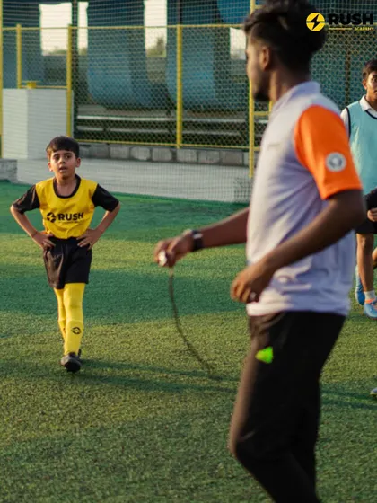 A coach watches over a young player, ready to offer guidance.