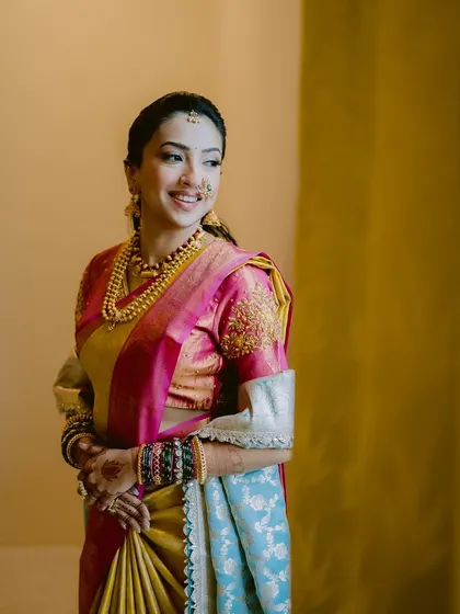 A beautiful, candid shot of a Maharashtrian bride. The makeup is kept natural and glowing to complement her multi-toned silk saree. The side profile highlights the delicate nath and the elegant, pulled-back hairstyle.