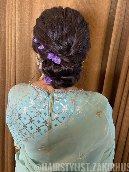 A back view of the romantic updo, showing the placement of the purple flowers and the soft, textured finish.
