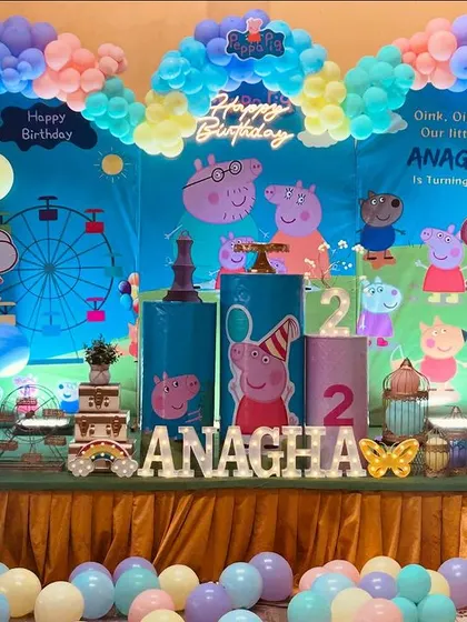 A large-scale Peppa Pig themed birthday party setup on a stage. The decoration includes a custom backdrop and colorful balloon arrangements.