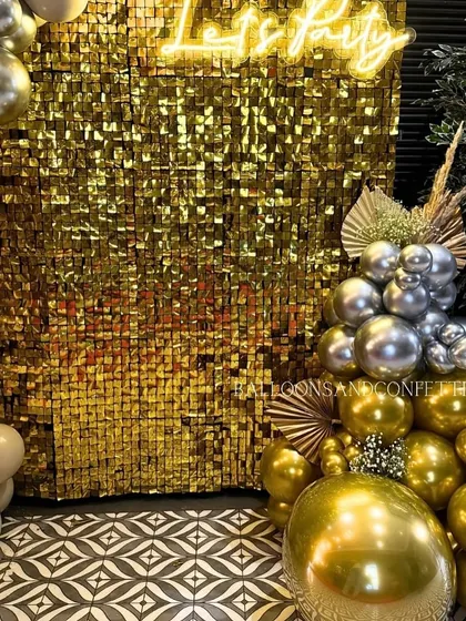 A detailed shot of the gold shimmer wall and the base of the balloon arrangement. I love adding dried floral elements like pampas grass to give metallic setups a softer, boho touch.