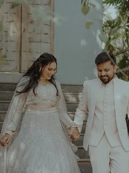 A couple walks hand-in-hand down a set of stairs at their wedding venue, sharing a happy, candid moment.