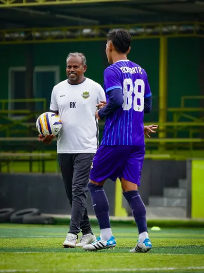 A moment of mentorship between a coach and player. This personal guidance is crucial for player development, helping them understand tactics and improve their game.