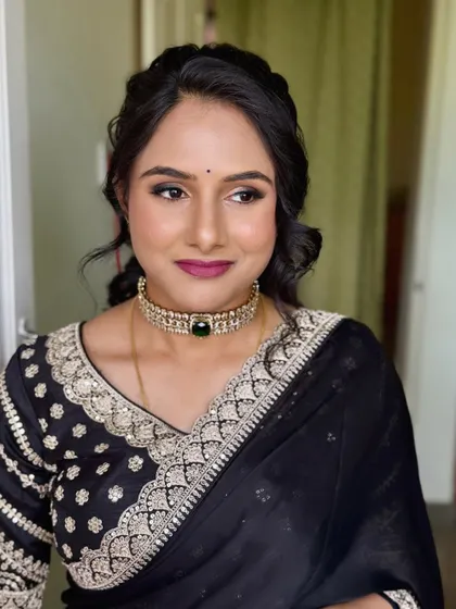A side view of Shwetha's makeup, showing the soft contouring and the intricate details of her hairstyle.