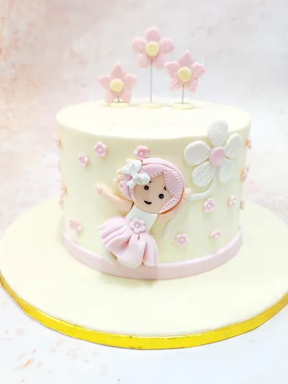 We design pure sweetness for a baby girl's first birthday with this girly flower cake. A charming fondant girl floats among pink and white flowers on a simple, elegant cake, creating a whimsical and delicate centerpiece.