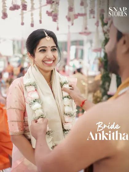 An over-the-shoulder shot of the groom placing the garland on his smiling bride. This perspective makes the viewer feel like part of the ceremony.