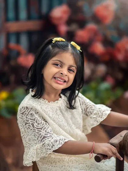A cheeky grin from this big sister. Her personality shines in this close-up from our floral garden sibling shoot.