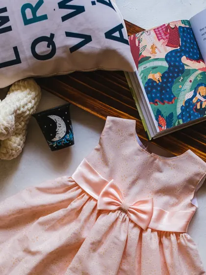 A simple and sweet pink dress with a gold shimmer, perfect for story time and quiet moments.