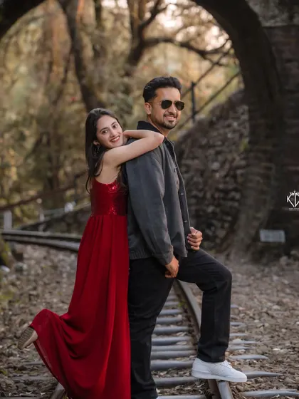 A playful and loving pose on the railway tracks, with the woman in a striking red dress. This image showcases the fun and comfortable connection between the couple.