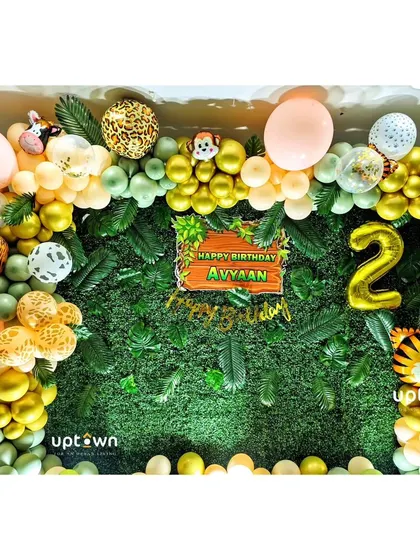 This photo booth backdrop uses a green foliage wall and a custom balloon garland with animal-print balloon's for a fun jungle-themed photo opportunity.