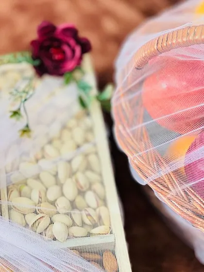 A detailed view of a dry fruit box next to a fruit basket. I pay close attention to the small details, like the single rose on the dry fruit box, to personalize each gift.