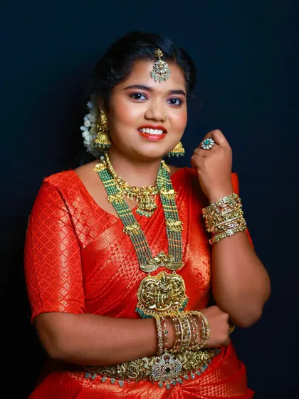 A portrait of the model, showing the contrast of the green beads against the red saree.