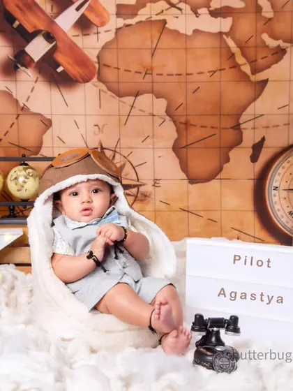 Ready for takeoff! This four-month-old pilot, Agastya, looks adorable in his aviator hat, set against a vintage world map.