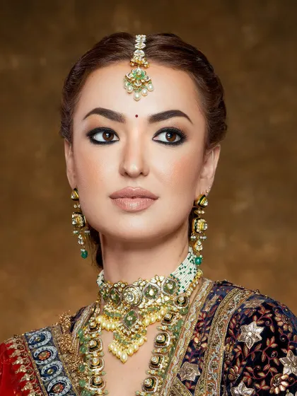 A close-up portrait of regal beauty, focusing on the flawless base, classic winged liner, and the intricate details of the heritage jewelry.