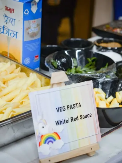 Our pasta station is ready for a party, complete with a cute, customized sign. We offer both white and red sauce options to cater to different preferences.