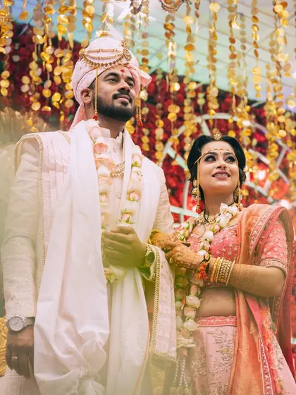 The couple stands together under a canopy of golden decorations, a beautiful shot capturing the wedding ambiance.
