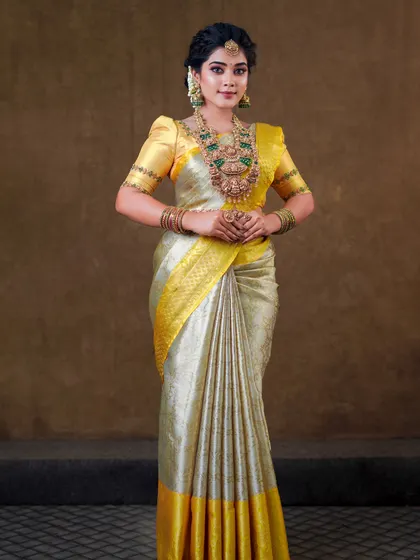 This silver and yellow silk saree creates a unique and elegant look. The draping is done to show off the beautiful contrast border and the richness of the silk.