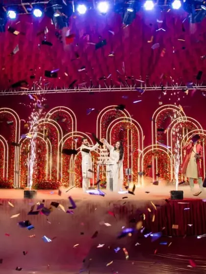 A wide shot of the Sangeet stage during a group performance, with confetti raining down on the dancers.