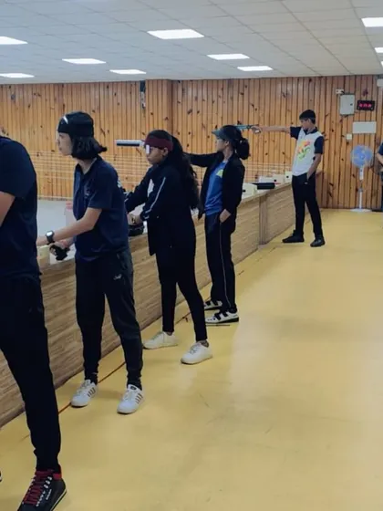 Students practice their 10-meter pistol shooting stances in a line. This image captures a typical training day where shooters work on consistency and aim under supervision.