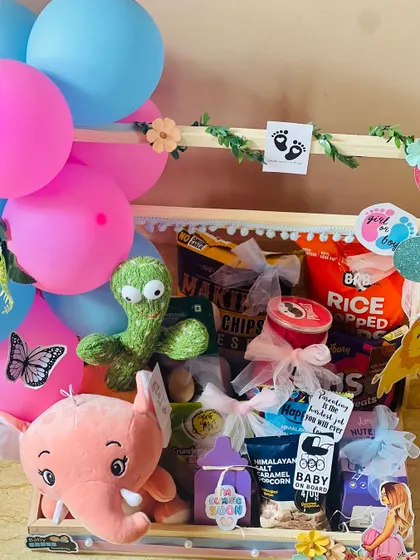 A closer look inside the whimsical baby shower cart. You can see the variety of snacks like popcorn and rice chips, all individually wrapped with care.