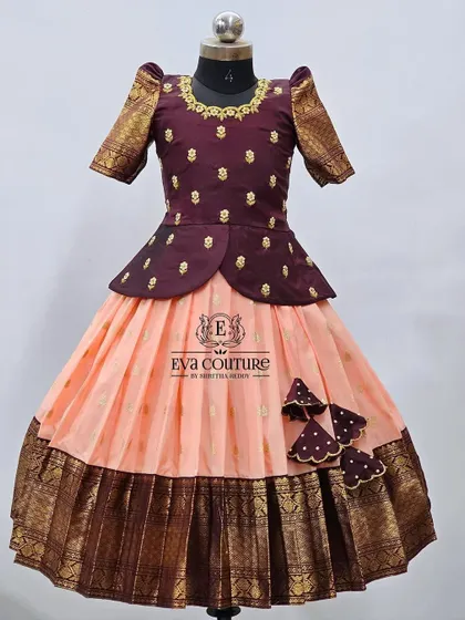 A variation of the design with a peach-colored skirt. The dark maroon peplum blouse with gold butti work pairs beautifully with the lighter skirt and its matching dark border.
