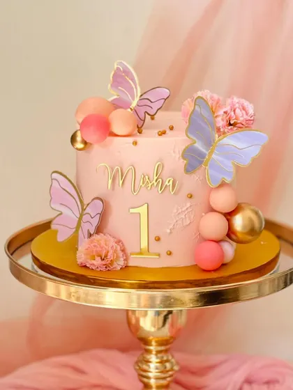 A pretty pink cake for Misha's first birthday. It's decorated with butterflies, flowers, and spheres in shades of pink and gold.