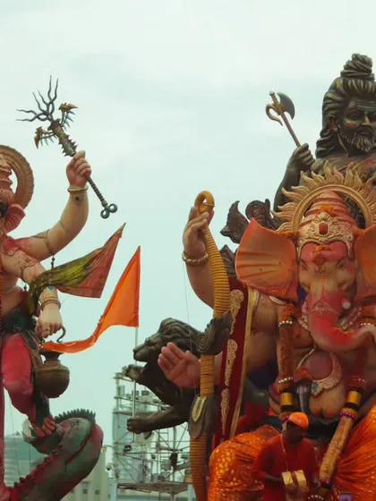 Two grand Ganesh idols side by side, showcasing the different artistic interpretations and the sheer spectacle of the procession.