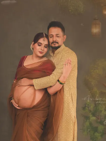 An intimate moment between the couple, captured within a rich, painterly setting. This portrait focuses on their connection, with the traditional attire and artistic backdrop adding layers of cultural depth and warmth to their maternity story.