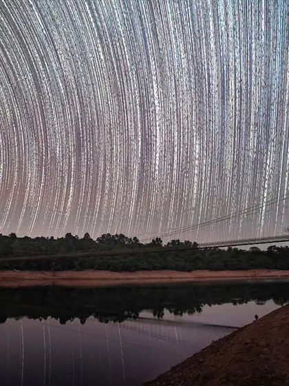 Star trails over a busy hanging bridge in the Western Ghats. Even with people and vehicles crossing, the long exposure captures the silent movement of the stars above.
