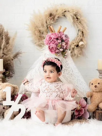 Celebrating six months with a boho-chic half-birthday shoot. The setup includes a lace teepee, pampas grass, and soft pink florals for a beautiful sitter session.